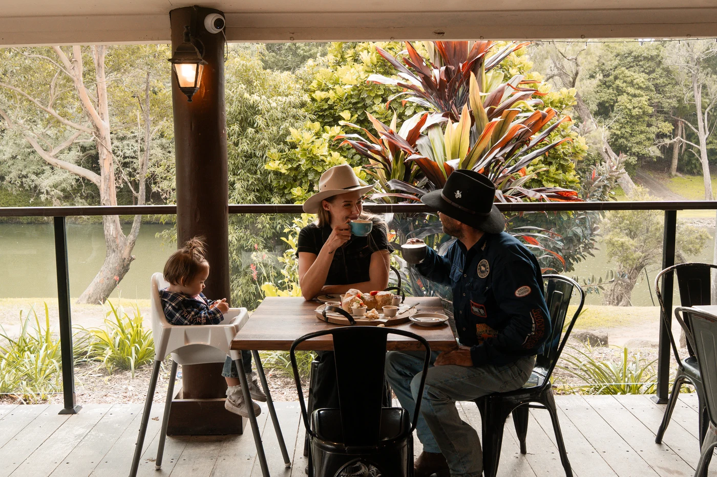 A family enjoying coffee and scones on the Rivermill Café deck overlooking the Coomera River