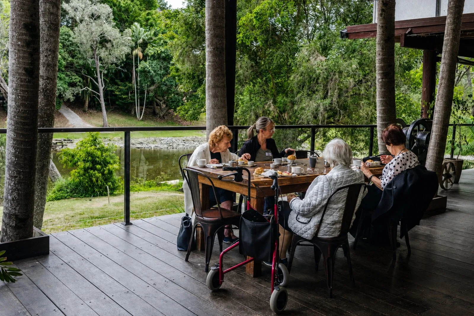 A seniors' group sharing a meal together on the deck overlooking the river